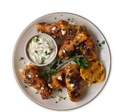 Yogurt-marinated grilled chicken wings with tzatziki sauce and pickled cucumbers
